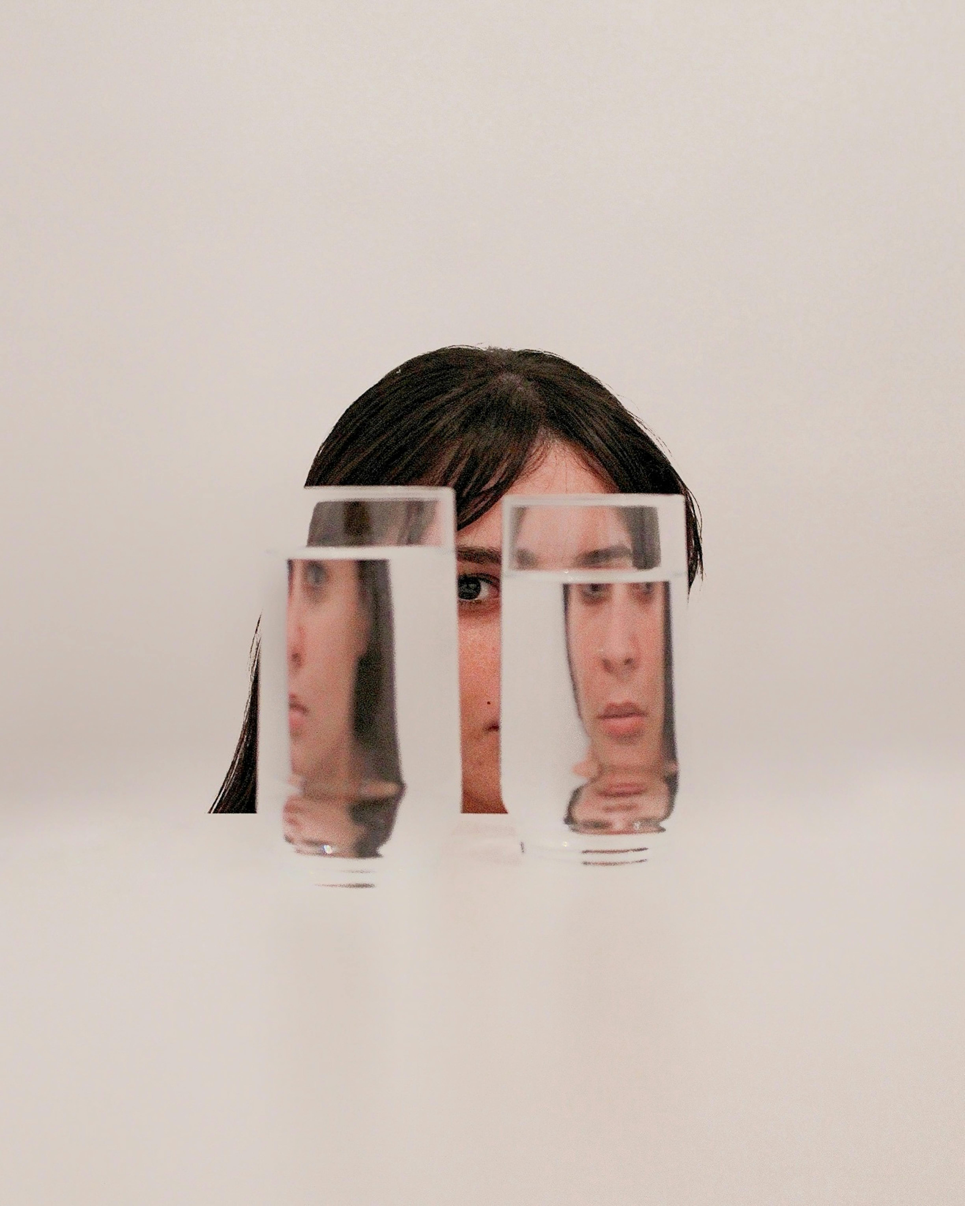 Portrait of the blog owner with face partially distorted through two clear glasses of water on a white table